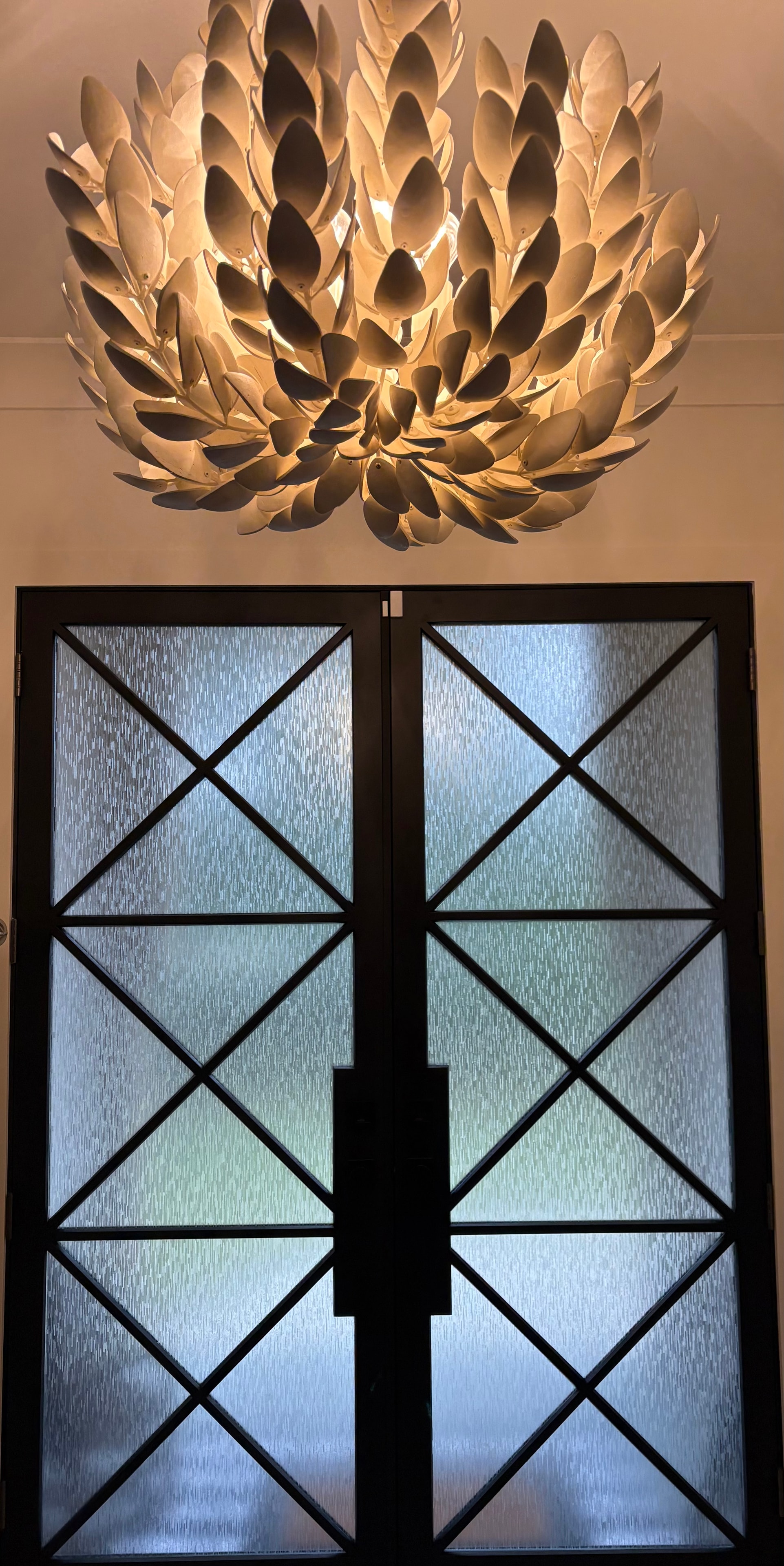 Completed SXHE-1034 Ice Forest decorative film on black-frame entry doors with leaf chandelier above
