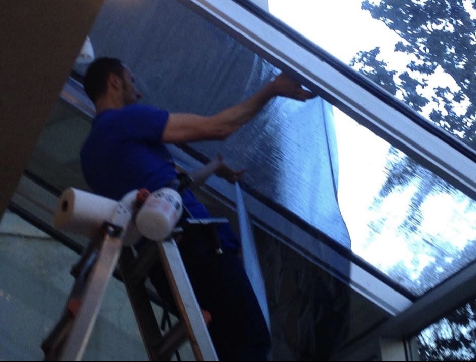 Technician applying window film to angled skylight glass