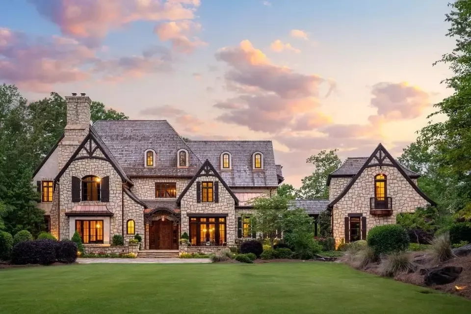 Luxury stone home with tinted windows at sunset