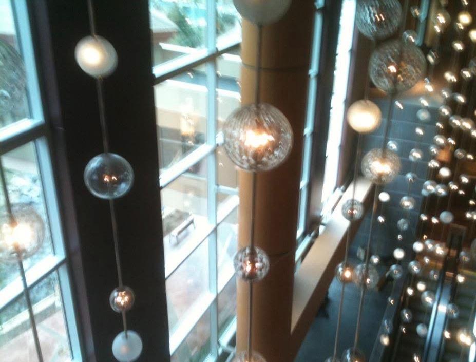 Large commercial atrium with globe pendant lights and floor-to-ceiling windows after tinting