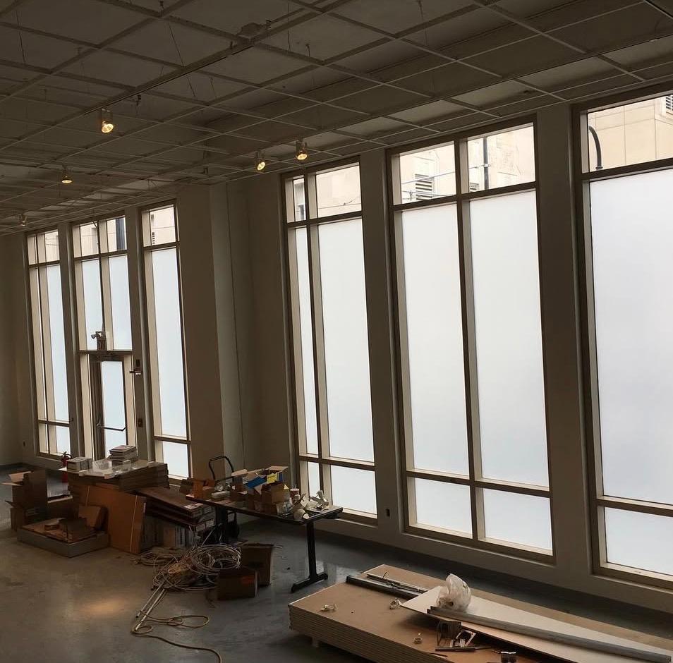 Commercial office space with frosted privacy film on tall windows during renovation