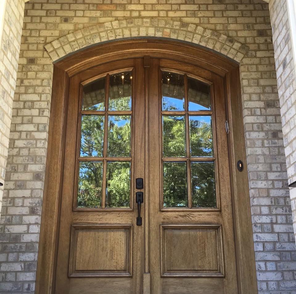 Elegant arched double front door with glass panes on brick home