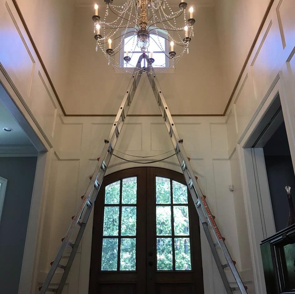 Grand foyer with tall arched door and ladder during window film installation