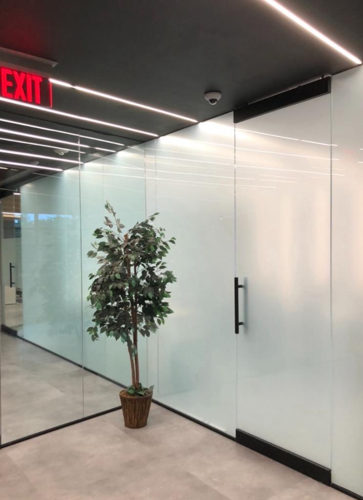 Modern office corridor with full-height frosted privacy film glass panels