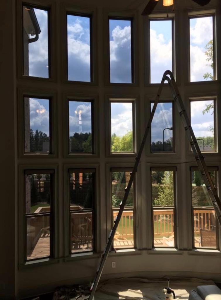Large two-story window wall with ladder during window film installation