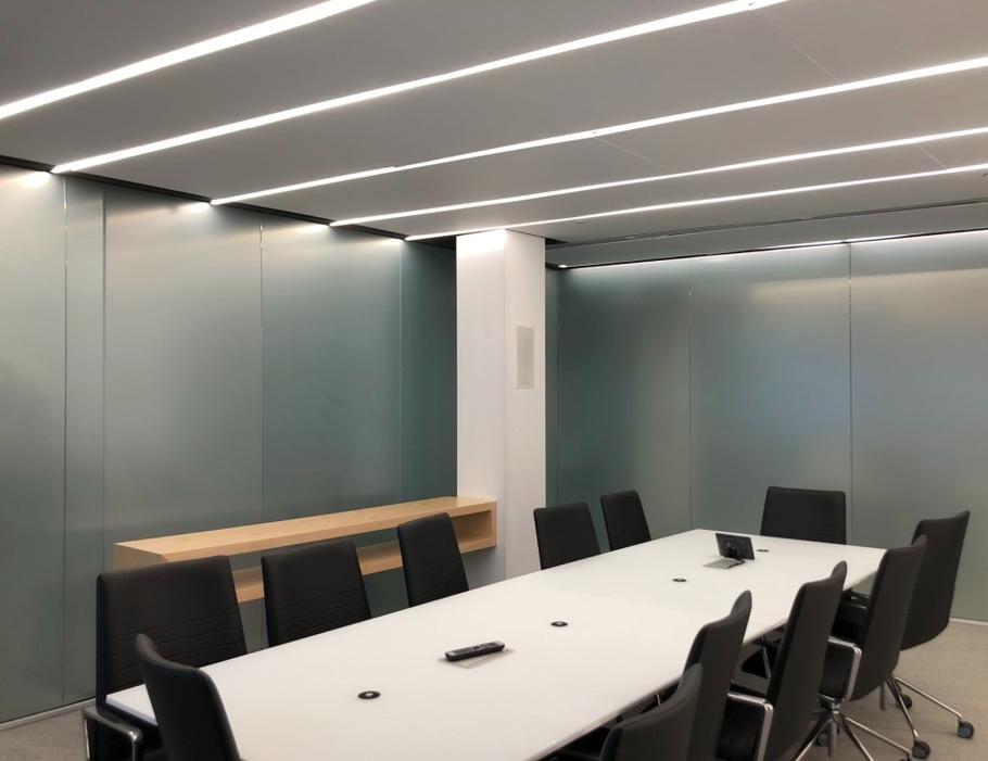 Modern conference room with frosted glass partition walls and linear ceiling lights