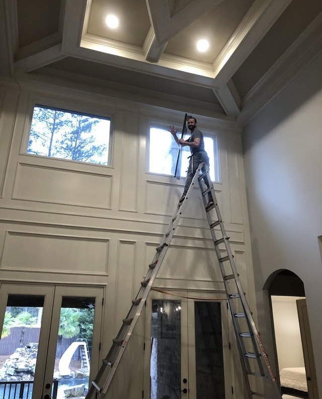 Sungate installer on ladder in luxury home foyer